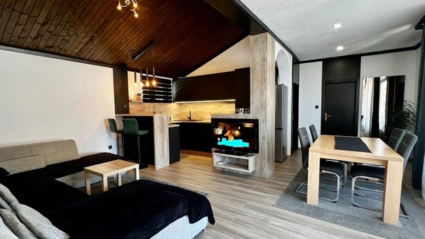 Una sala moderna con sofá, una mesa de comedor y una zona de cocina con televisor.