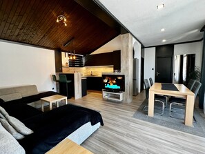 Un salon moderne comprenant un canapé, une table à manger et un coin cuisine avec un téléviseur.