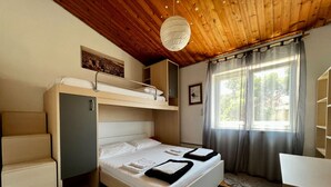 Una habitación pequeña con una cama individual superpuesta, un escritorio, una silla, un armario y una ventana con cortinas.