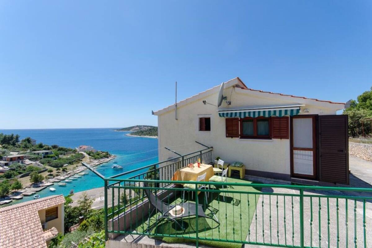 A coastal property with a balcony overlooking a swimming pool and the sea.
