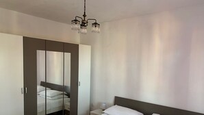 A bedroom with a bed, a nightstand, a mirror, and a wardrobe. - Apartments Josip (Rogoznica)