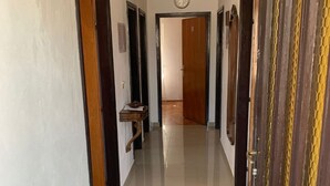 A hallway with a tiled floor, wooden doors, and a clock on the wall. - Apartments Josip (Rogoznica)