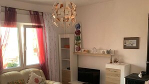 A living room with a sofa, TV, and a fireplace. - Apartments Josip (Rogoznica)