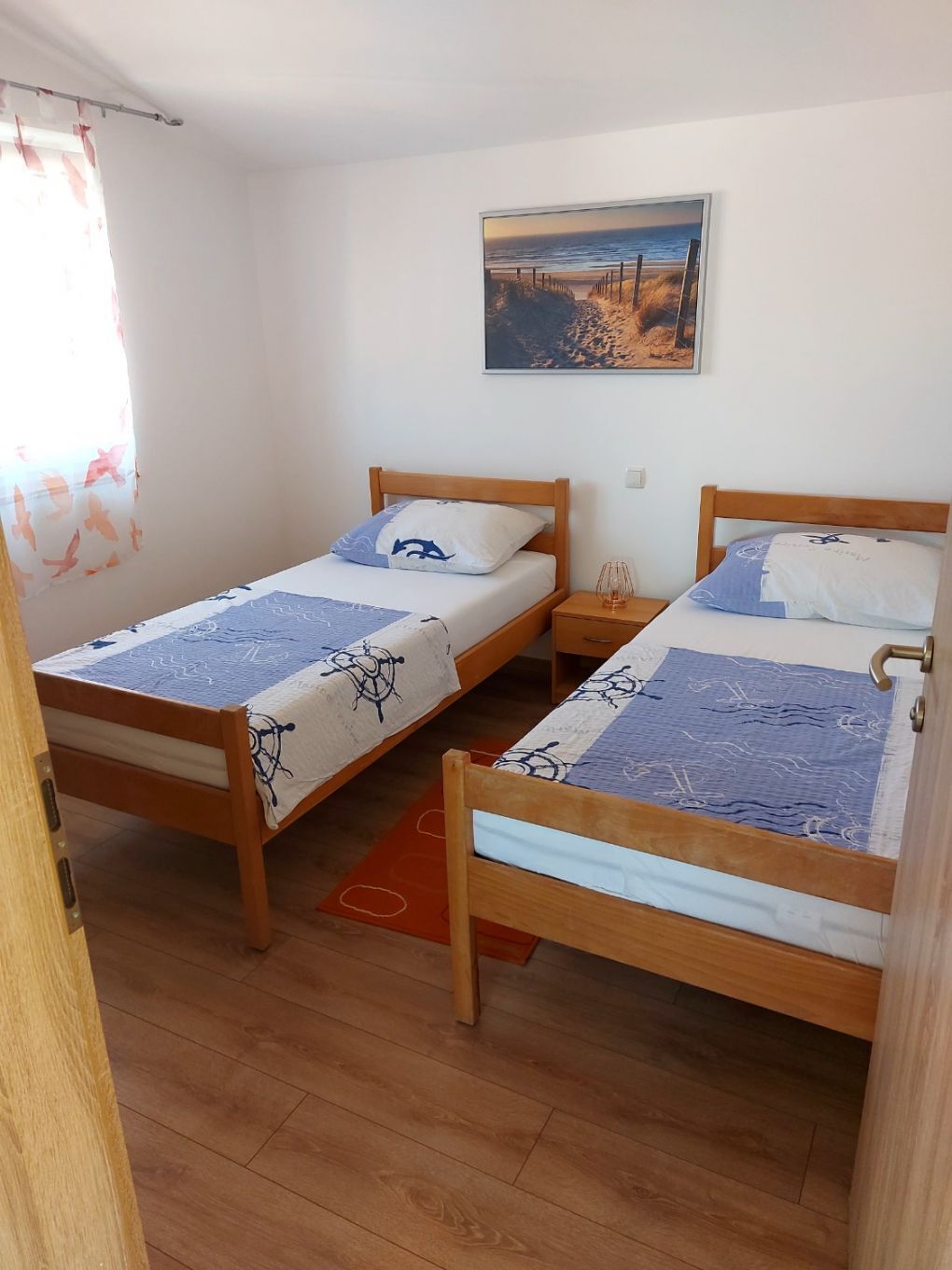 A room with two wooden beds, each with a matching headboard and footboard, and a single nightstand between them.