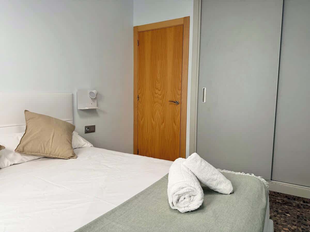A hotel room with a bed, a wooden door, a wardrobe, and a towel on the bed.