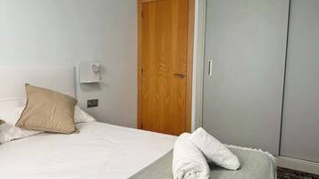 A hotel room with a bed, a wooden door, a wardrobe, and a towel on the bed.