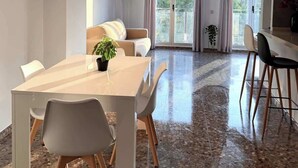 Un comedor moderno con una mesa larga, sillas blancas y una planta en maceta.