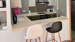 Una cocina moderna con una isla central, dos taburetes de bar y un florero con flores.