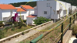 A residential area with white buildings, red-tiled roofs, and a green metal railing. - Apartment Bubi (Solta)