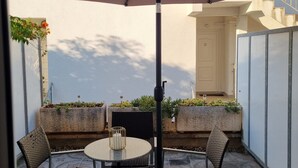 An outdoor patio with a round table and four chairs, a large umbrella, and planters with greenery. - Apartment Bubi (Solta)
