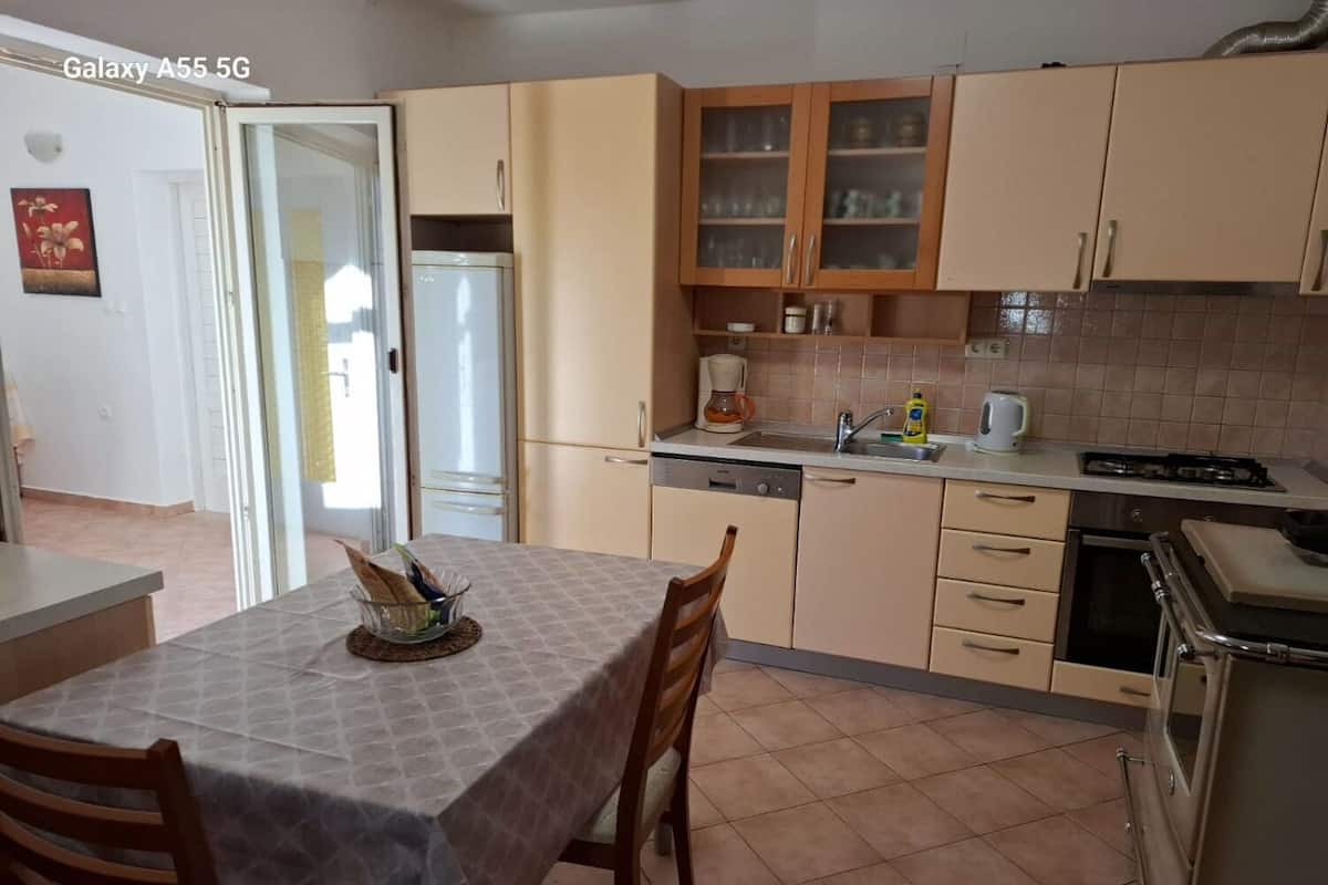 Une cuisine compacte comprenant une table à manger, des chaises, un réfrigérateur, une machine à café et une cuisinière.