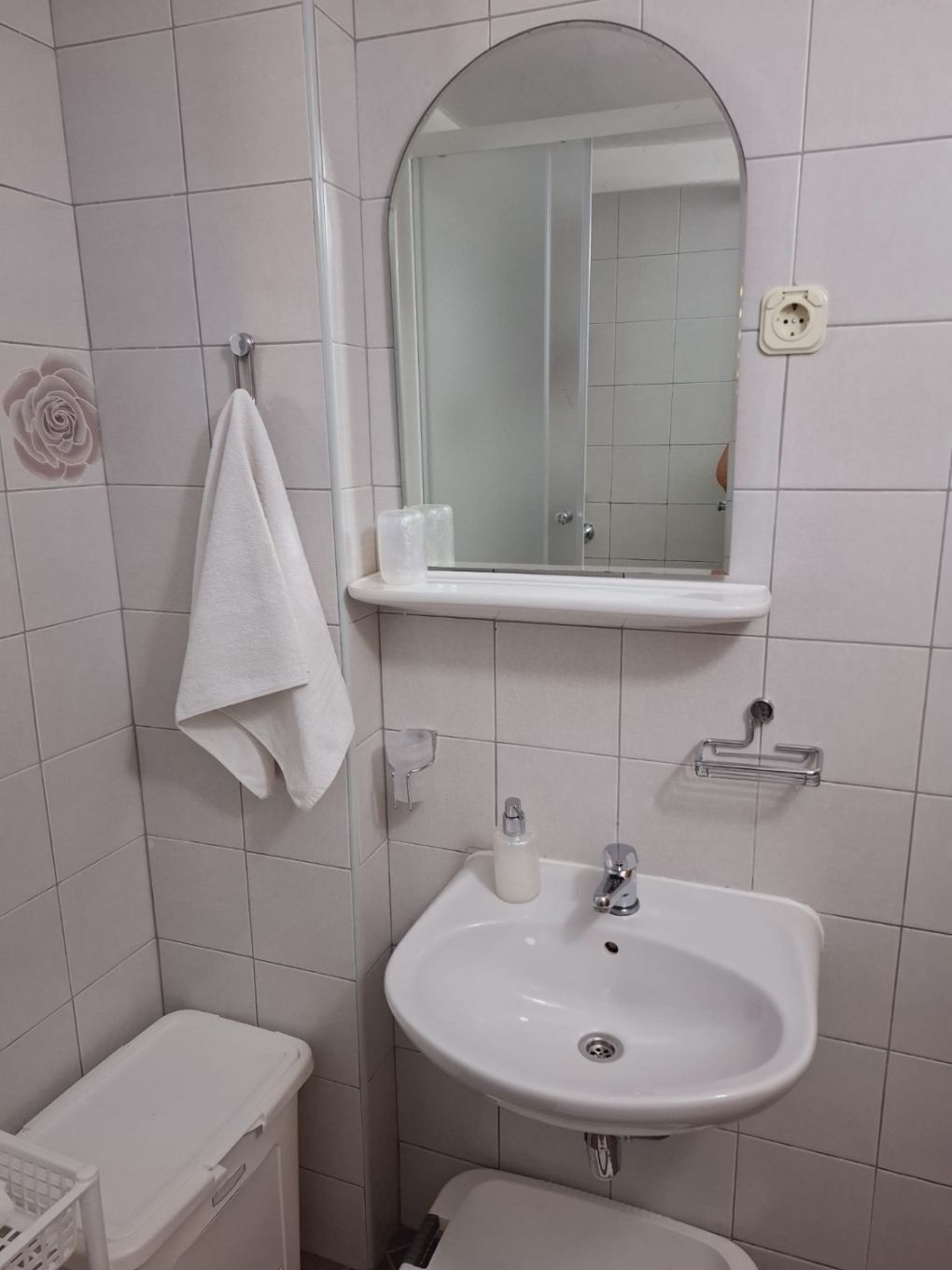 Un bany amb un lavabo blanc, un mirall, una tovallola penjada a l'assegador i un vàter.