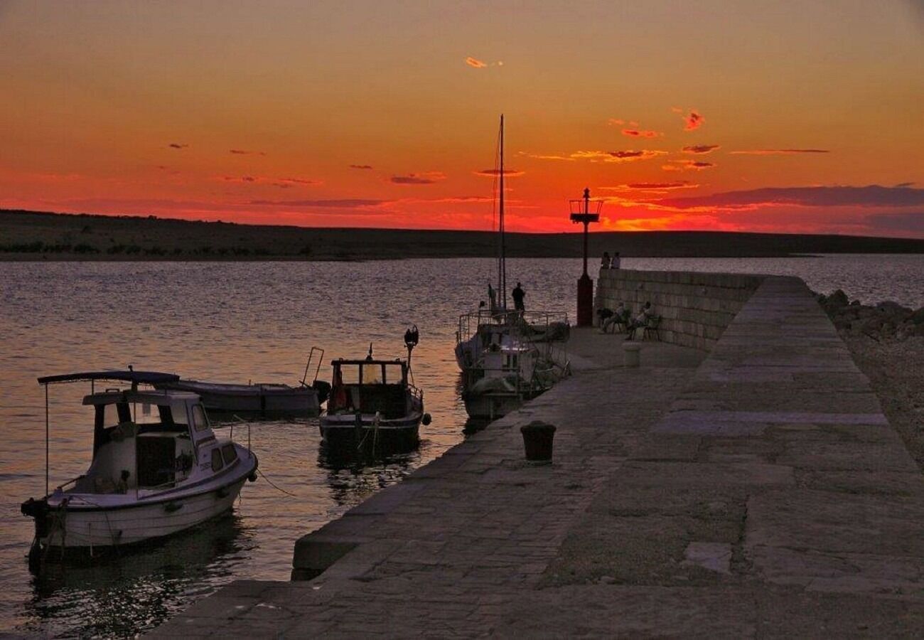 A waterfront scene with boats docked at a pier during sunset.