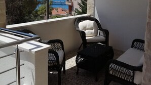 A balcony with a view of the sea, featuring wicker furniture and a metal railing. - Apartment Vesna (Trogir)