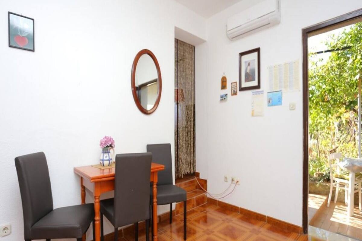 A dining area with a wooden table, four chairs, a mirror, and a door leading to a balcony.