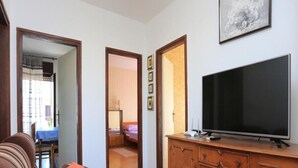 A living room with a sofa, a TV on a wooden cabinet, and a door leading to another room. - Apartments Rosa (Split)