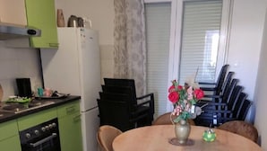 A compact kitchen with green cabinets, a dining table with four chairs, and a window with blinds. - Apartments Rosa (Split)