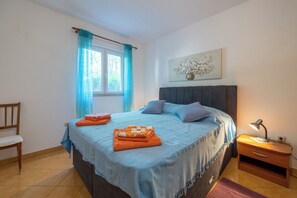 A bedroom with a bed, a chair, a nightstand, and a window with curtains. - Apartment Perka (Jelsa)