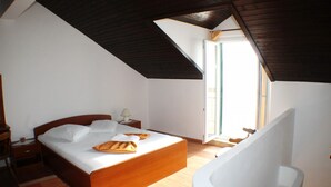 Un dormitorio con cama de madera, una mesita de noche, una lámpara y una bañera blanca.