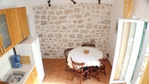 Una cocina compacta con pared de piedra, una mesa de comedor con sillas y un refrigerador.