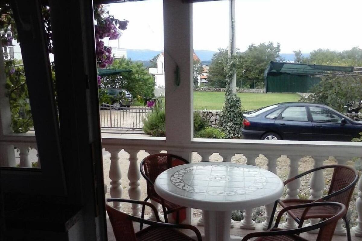 A covered outdoor seating area with a round table and four chairs.