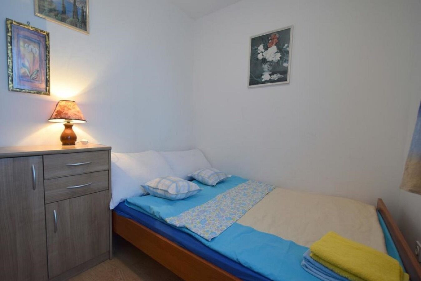 Una camera da letto con un letto, un comodino, una lampada e una cassettiera.