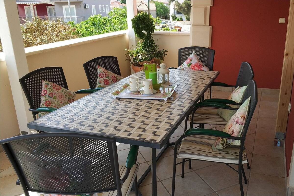 A dining area with a checkered table, green chairs, and a potted plant.