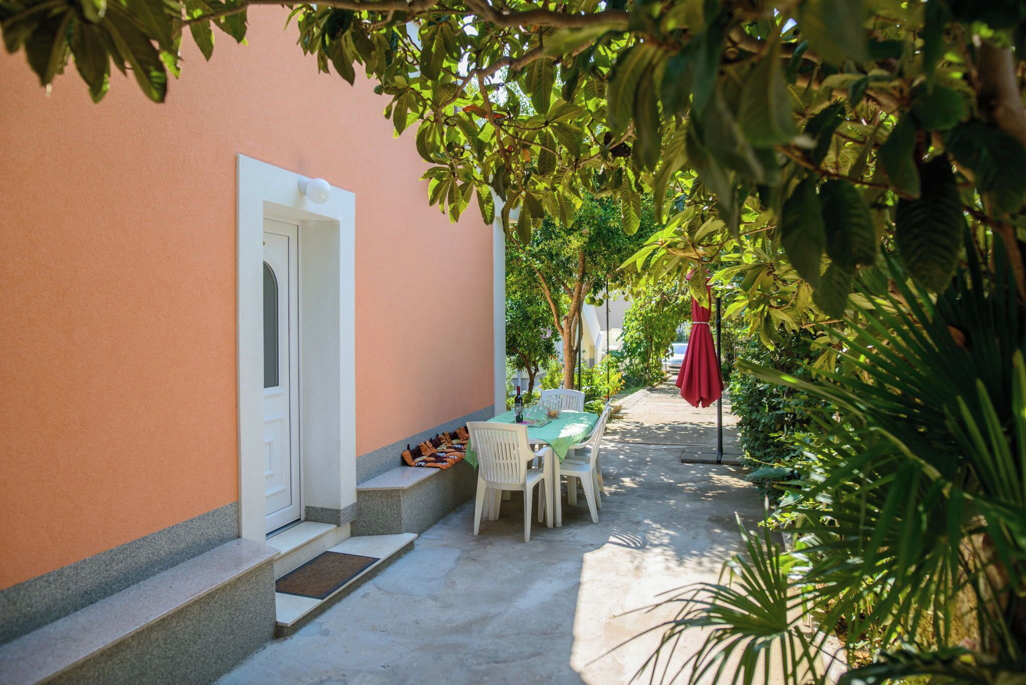 A patio with a table and chairs, a door, and steps leading to a building.