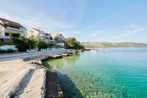 Un hôtel situé sur la côte, avec une eau cristalline, une plage de sable et un quai pour bateaux.