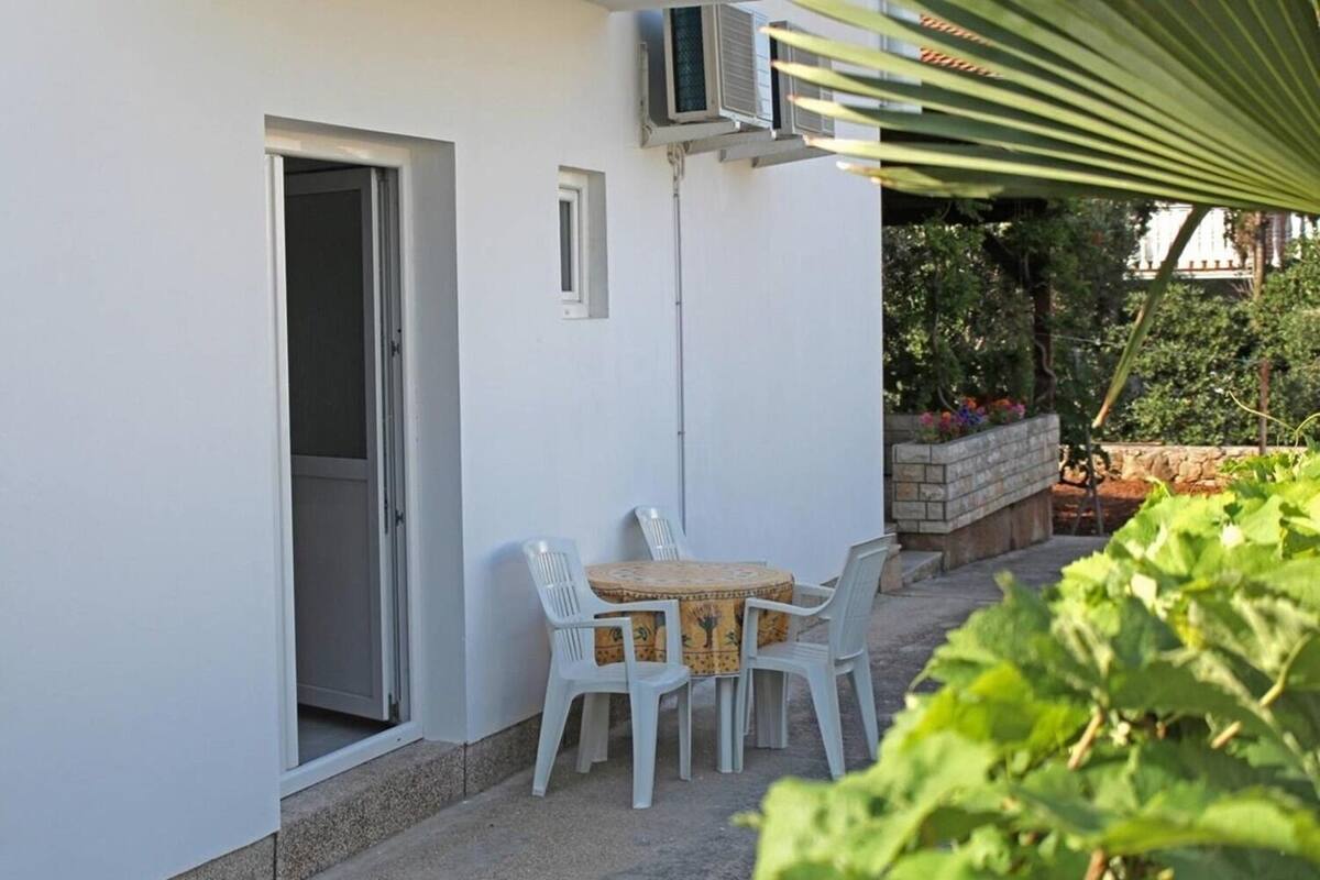 Eine Terrasse mit Tisch und Stühlen, einer Klimaanlage und einer Tür.