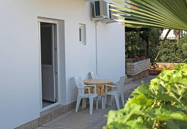 Patio con tavolo, sedie, condizionatore d'aria e una porta.