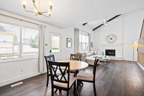 Un salon moderne comprenant un coin repas, de grandes fenêtres, un ventilateur de plafond et une horloge murale.