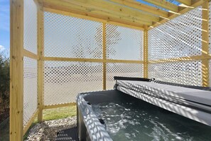 A hot tub with a wooden frame and perforated metal walls, surrounded by gravel. - Nookside Grand Estate For 8 (Hamilton)