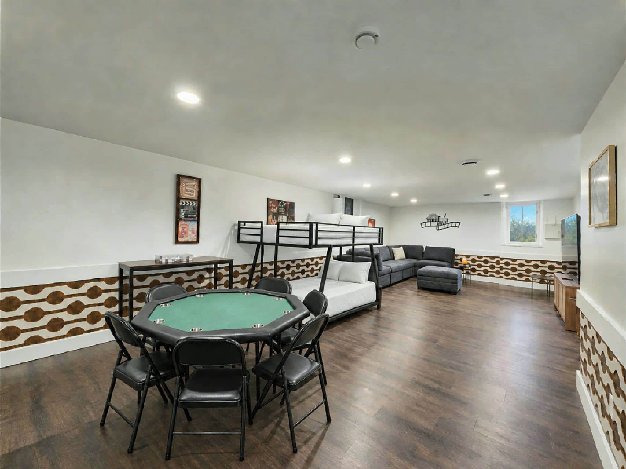 Una habitación con mesa de billar, sofá y literas.