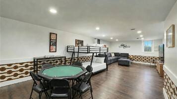 Una habitación con mesa de billar, sofá y literas.
