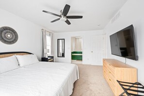A bedroom with a bed, a ceiling fan, a TV, a dresser, and a mirror. - Nookside Grand Estate For 8 (Hamilton)