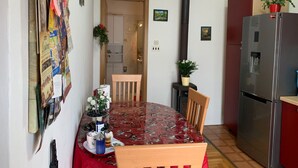 A dining area with a round table, chairs, a clock, a stove, and a refrigerator. - Apartment Tomi (Hvar)