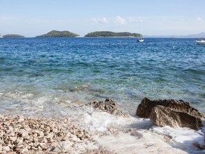 Una playa despejada con primer plano rocoso y mar tranquilo.