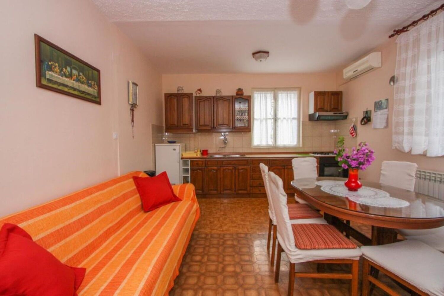 Ein kompakter Wohnraum mit Sofa, Esstisch, Stühlen und einer Küchenzeile.