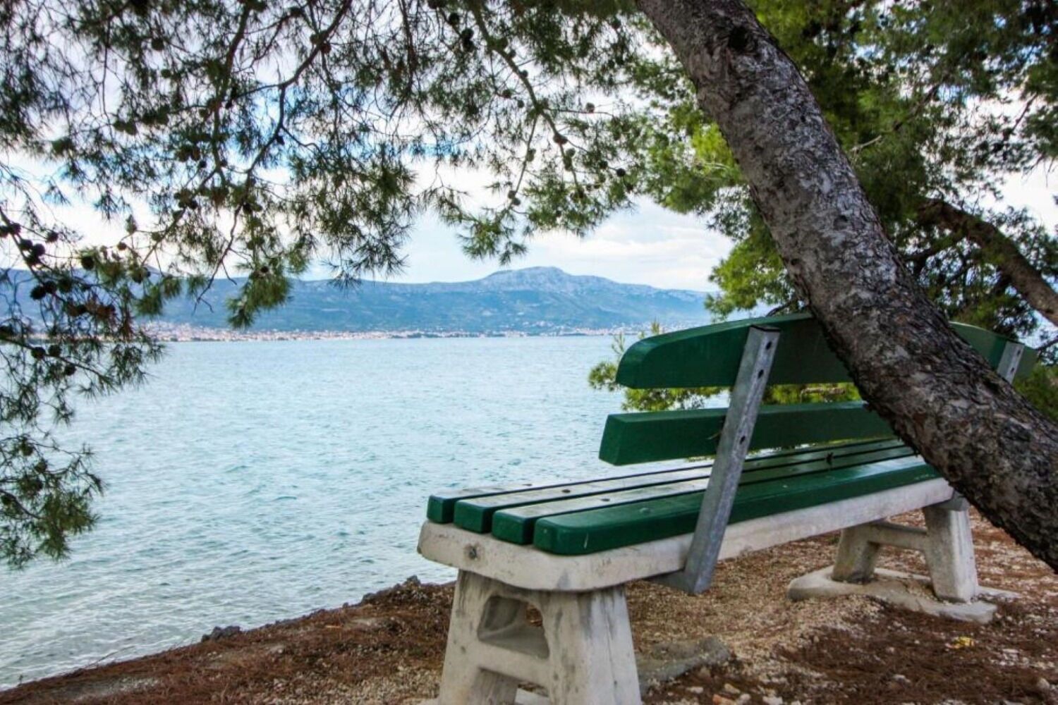 A bench by a lake with a view of mountains in the distance.