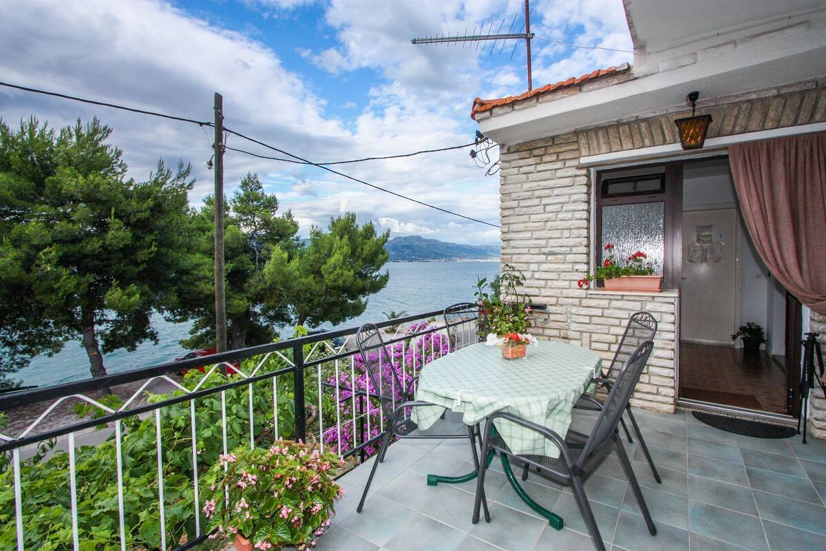 A balcony with a table and chairs, overlooking a body of water and trees.