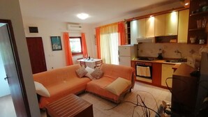 A compact living space with a sofa, a small table, a kitchenette, and a dining area. - Apartment Goran (Solta)