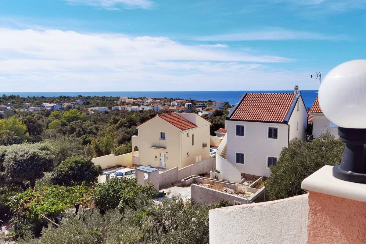 A coastal residential area with houses, a clear sky, and a view of the sea.