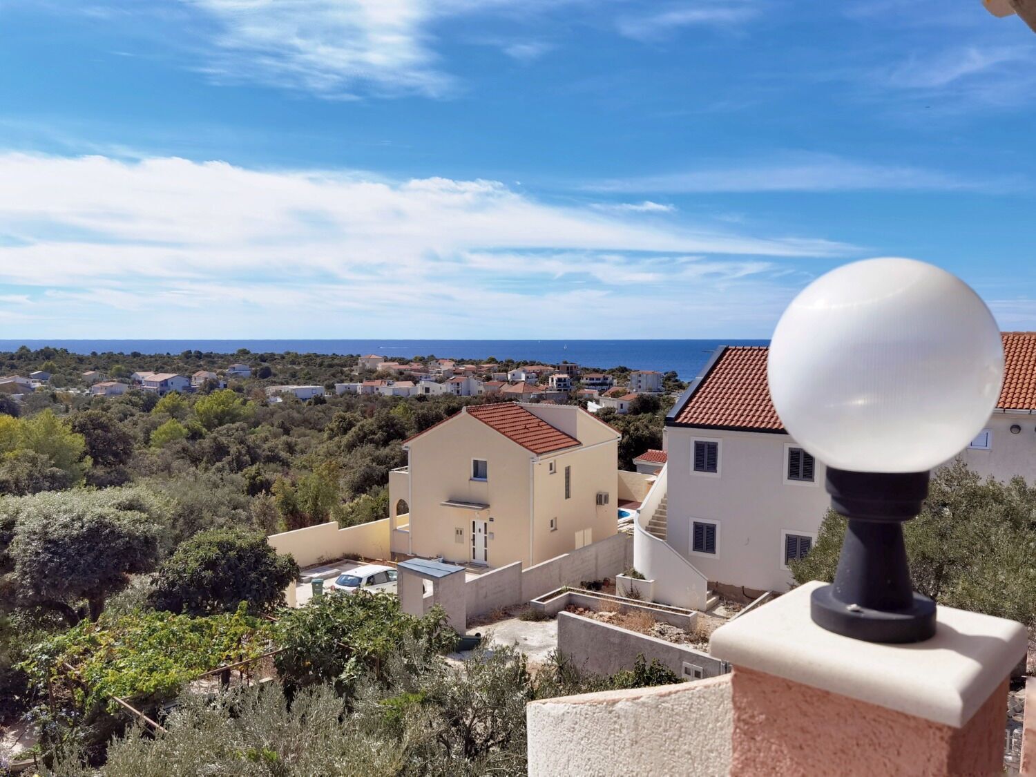 Eine Küstenwohngegend mit Häusern, blauem Himmel und Blick auf das Meer.