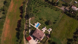 Vista aérea de una propiedad con un edificio principal, una piscina y follaje circundante.