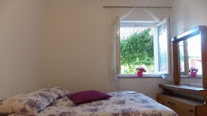 A bedroom with a bed, a dresser, a window with a view of greenery, and a mirror. - House Andro (Bibinje)