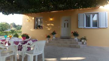 Un patio al aire libre con una mesa, sillas, una puerta y plantas en macetas.