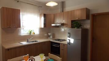 Una cocina moderna con armarios de madera, un refrigerador de acero inoxidable, una estufa a gas y una ventana con plantas en macetas.