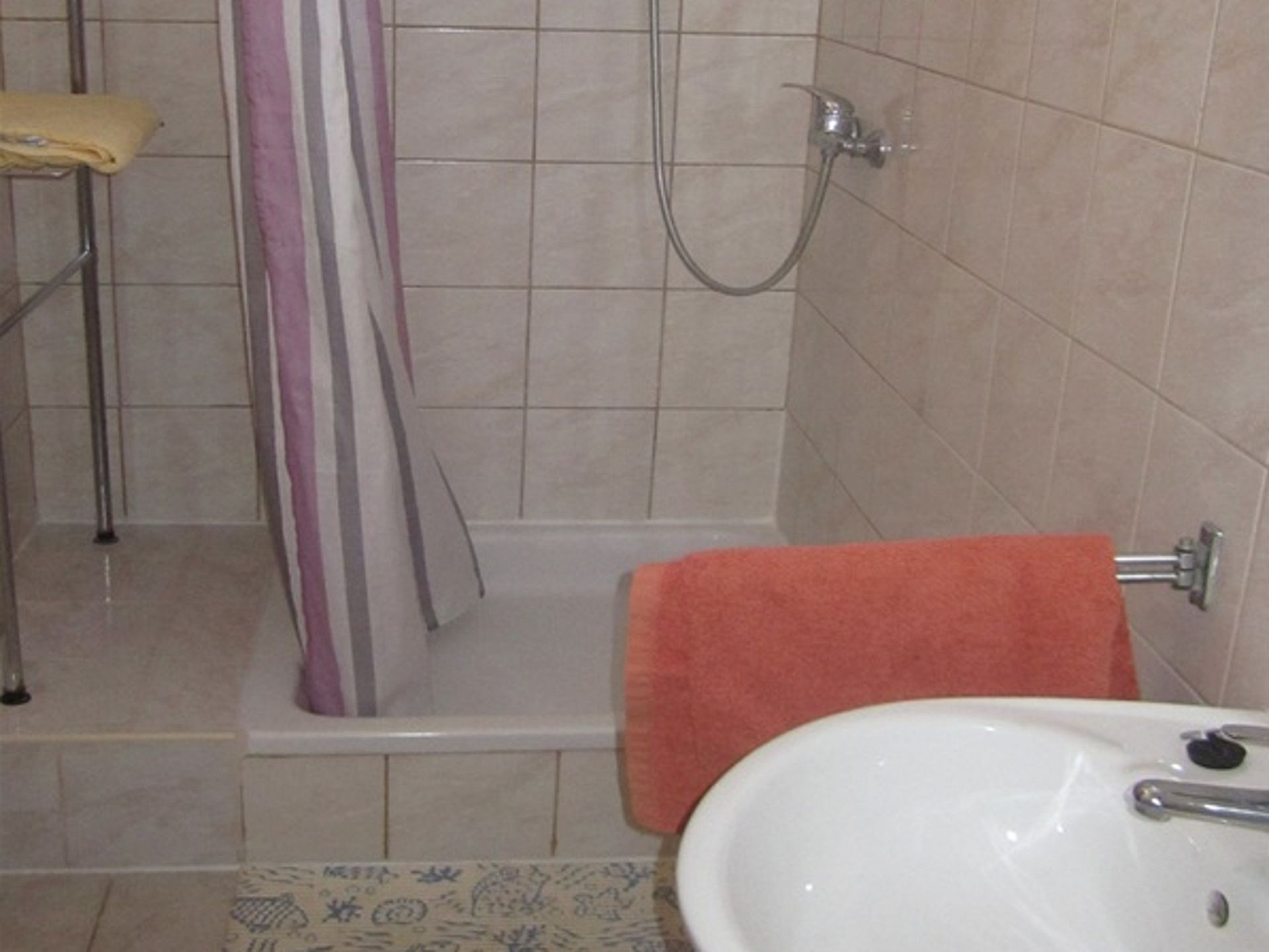 Ein Badezimmer mit Dusche, Waschbecken und Handtuchhalter.