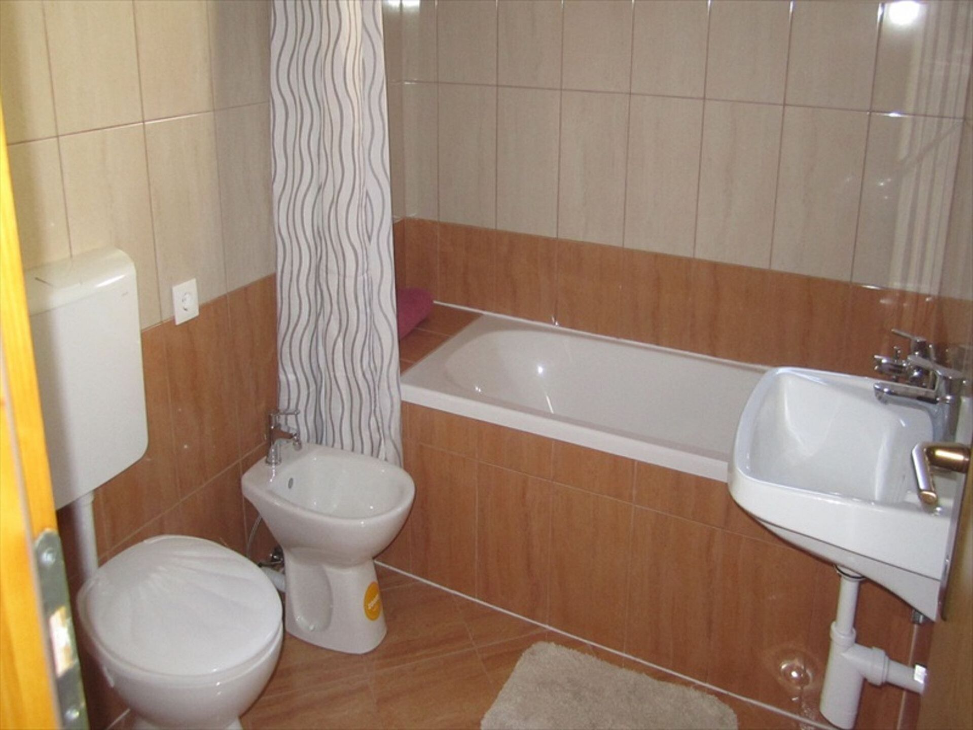 A bathroom with a toilet, bidet, bathtub, and sink.